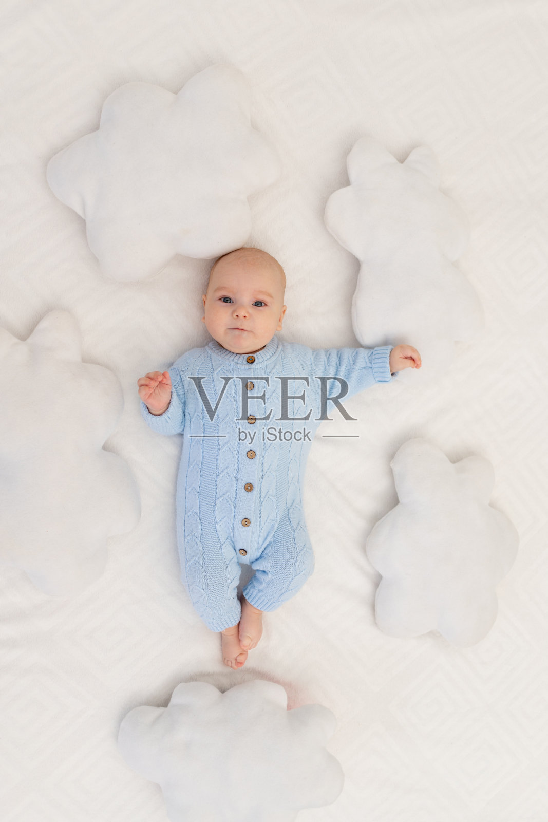 婴儿躺在床上，枕着云朵。纺织品和儿童床上用品。照片摄影图片