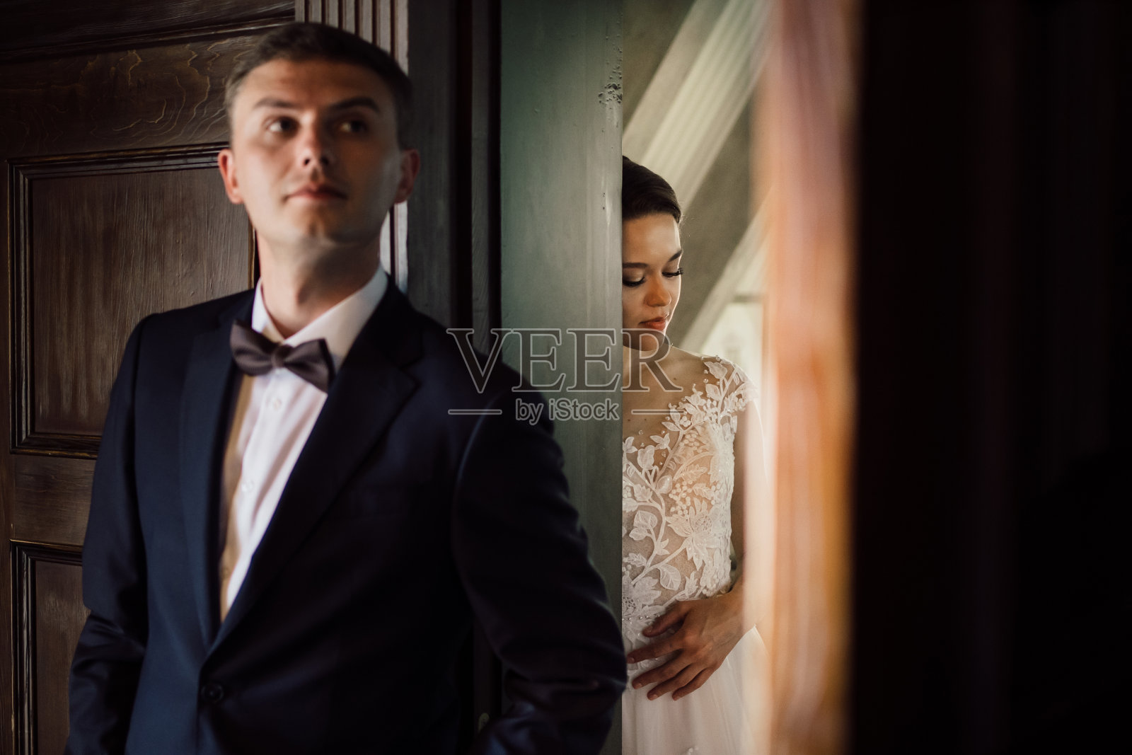 第一次见面前，新娘和新郎隔着墙在门口交谈照片摄影图片
