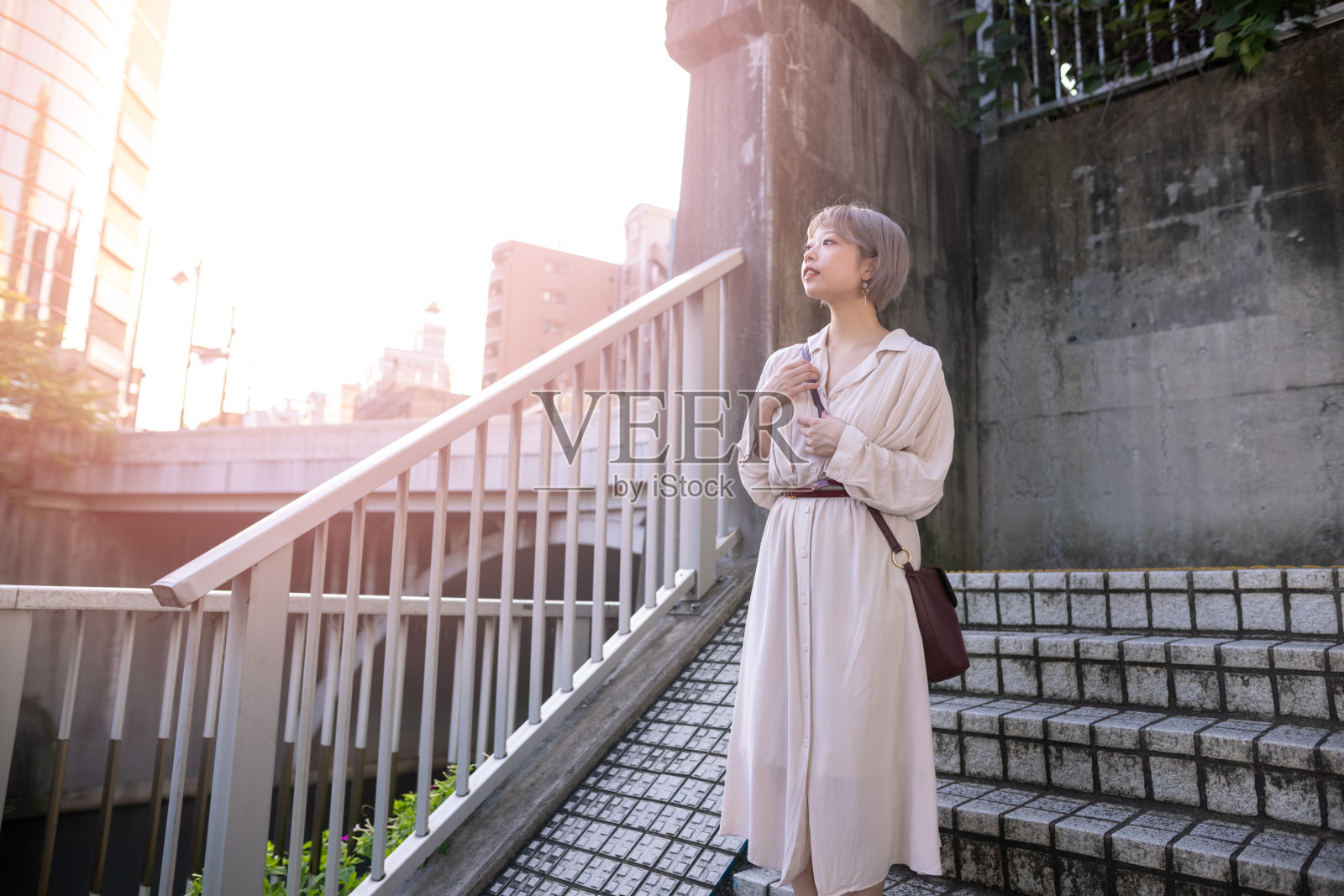年轻女子走下楼梯，看日落时分的风景照片摄影图片