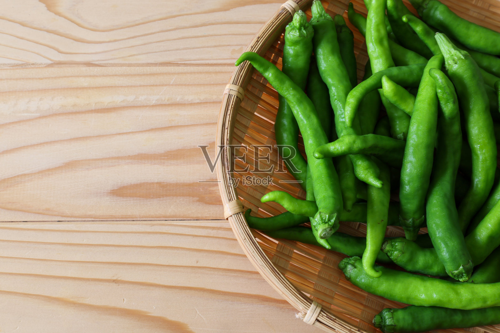 甜椒放在竹制滤锅上，孤立在一张白色木桌上。照片摄影图片