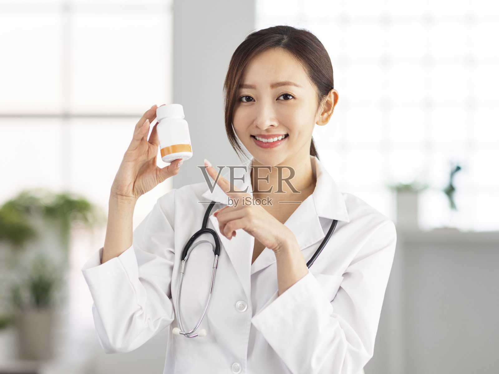 医生微笑着指着一罐药丸。照片摄影图片