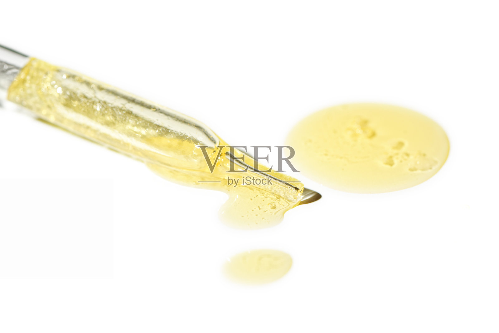 液体油血清滴在移液管分离在白色背景。视黄醇，aha, bha酸，胶原蛋白护肤液，浅景深照片。黄金精华滴在美容护理照片摄影图片