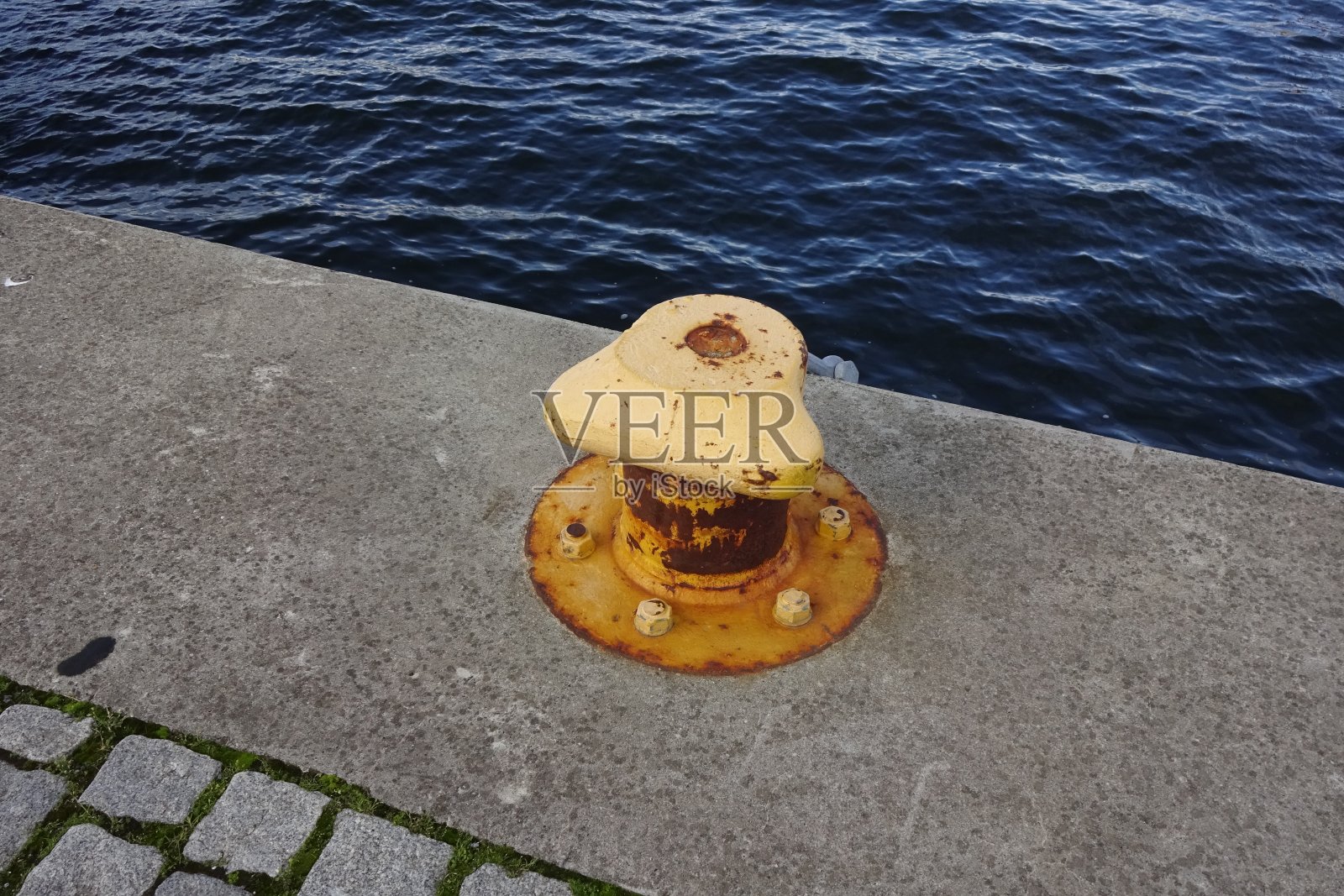 靠近老生锈的黄色系泊柱在石墩与铺路。海军海水。夏天,2021年8月。爱沙尼亚塔林照片摄影图片