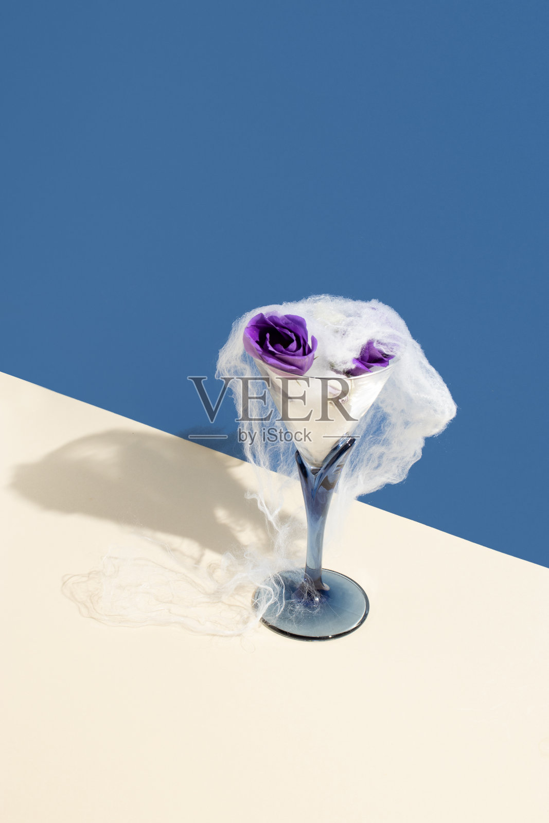 有创意的万圣节布局与葡萄酒杯，蜘蛛网和花朵的蓝色背景。创意假日派对概念。照片摄影图片