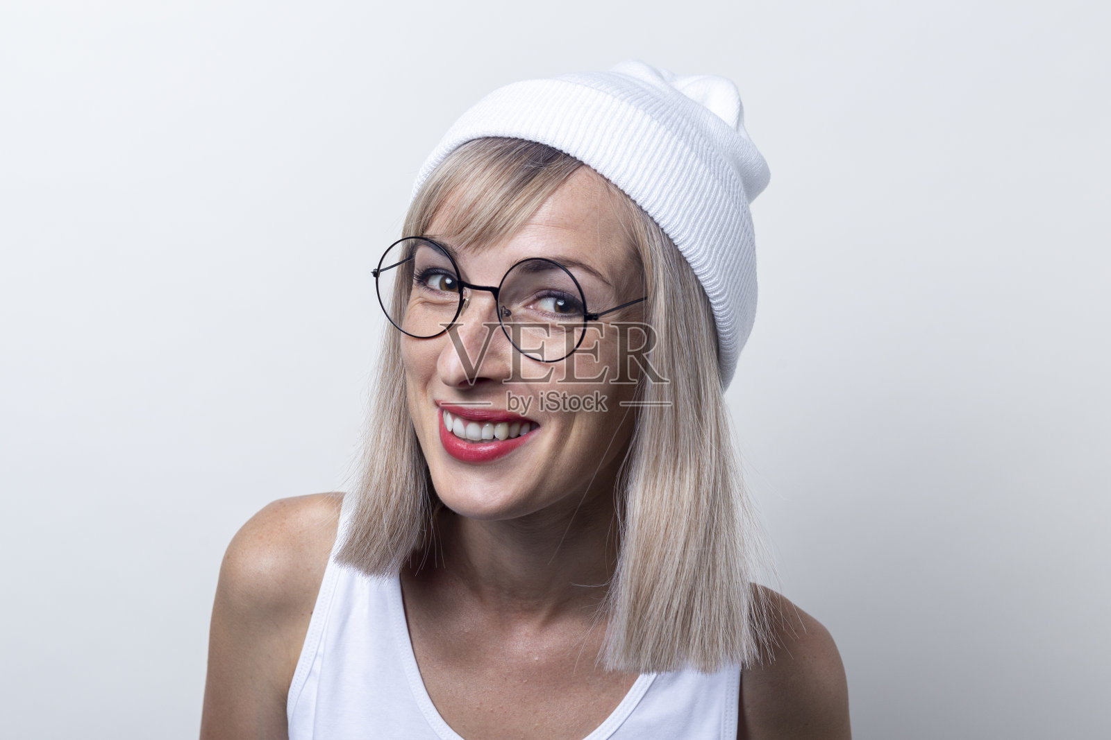 一个戴着眼镜，身穿白色t恤的微笑的年轻女子，背景是浅色的照片摄影图片