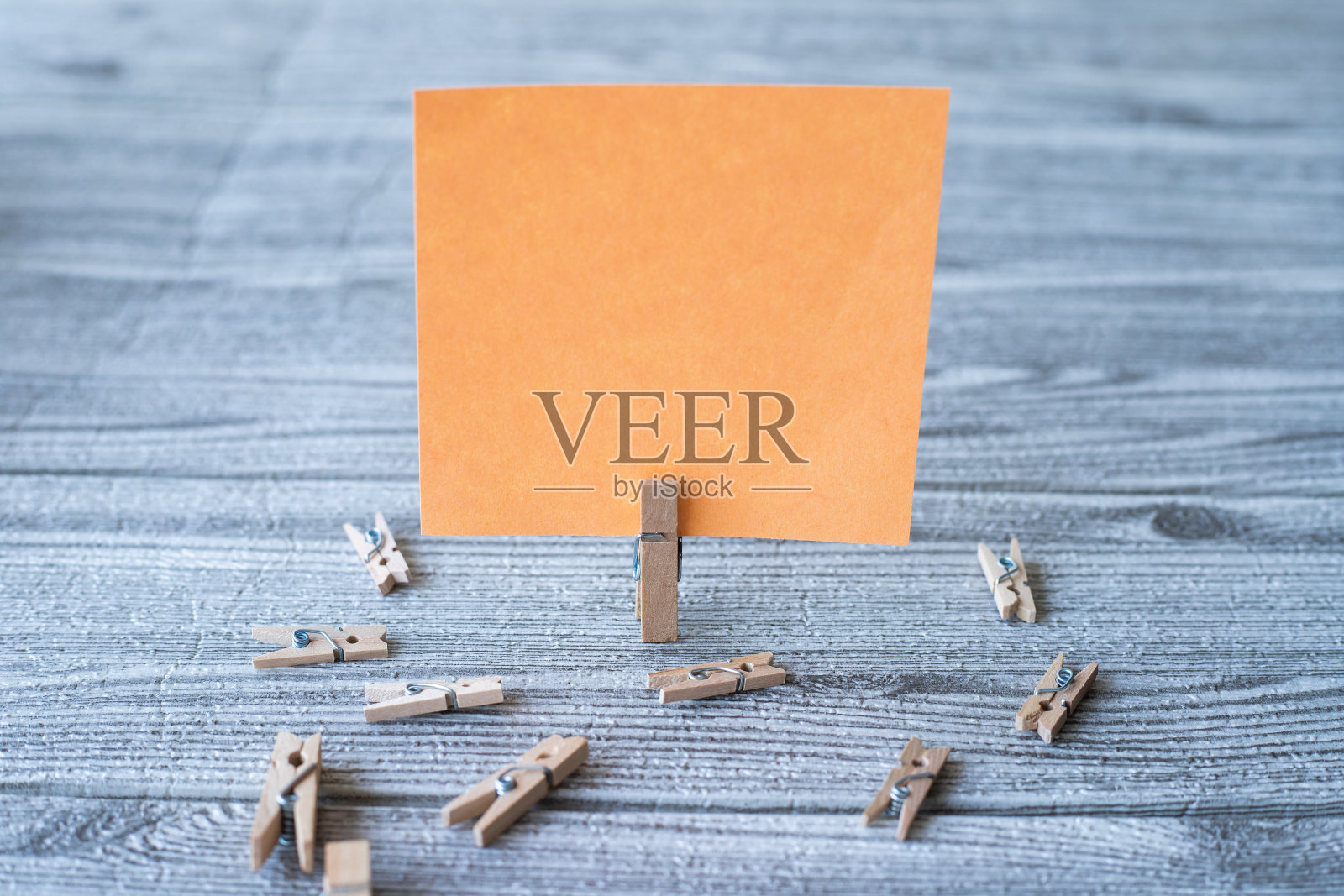 一块空白的正方形笔记被洗衣夹包围显示新的意义。空粘纸夹直立放置在木桌顶部显示新鲜的想法。照片摄影图片