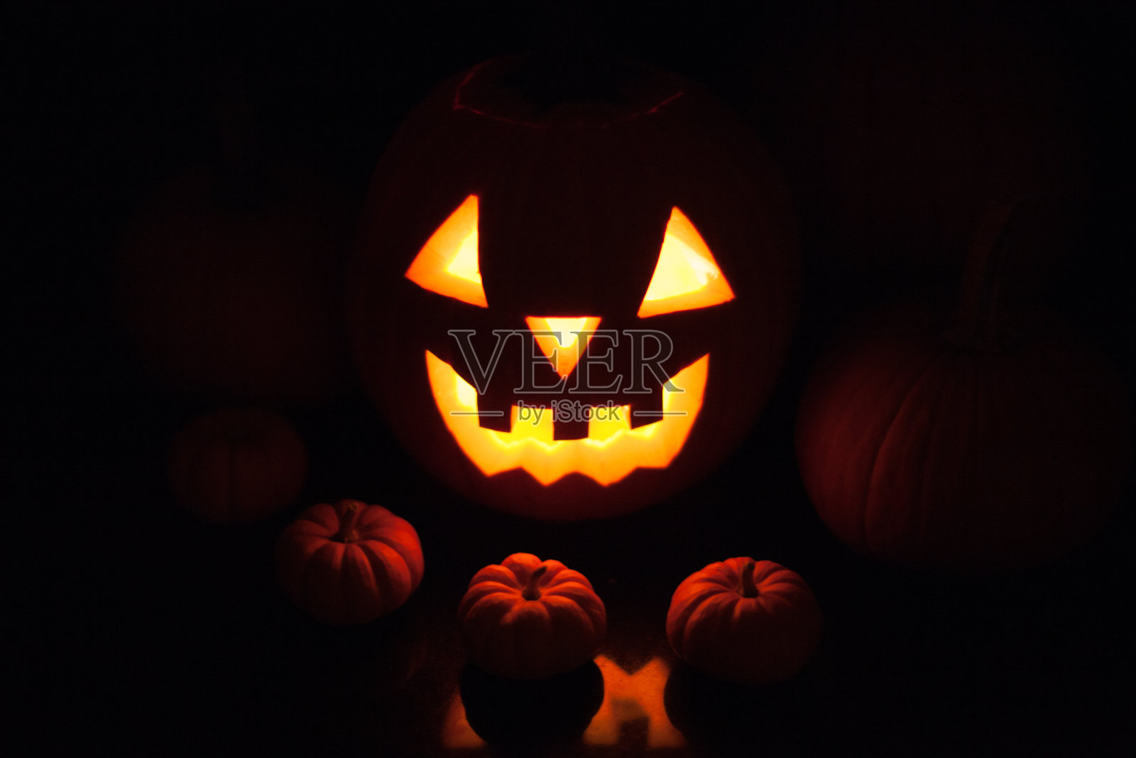 一个巨大的手工制作的万圣节杰克灯在黑暗的黑色背景蜡烛照明照片摄影图片