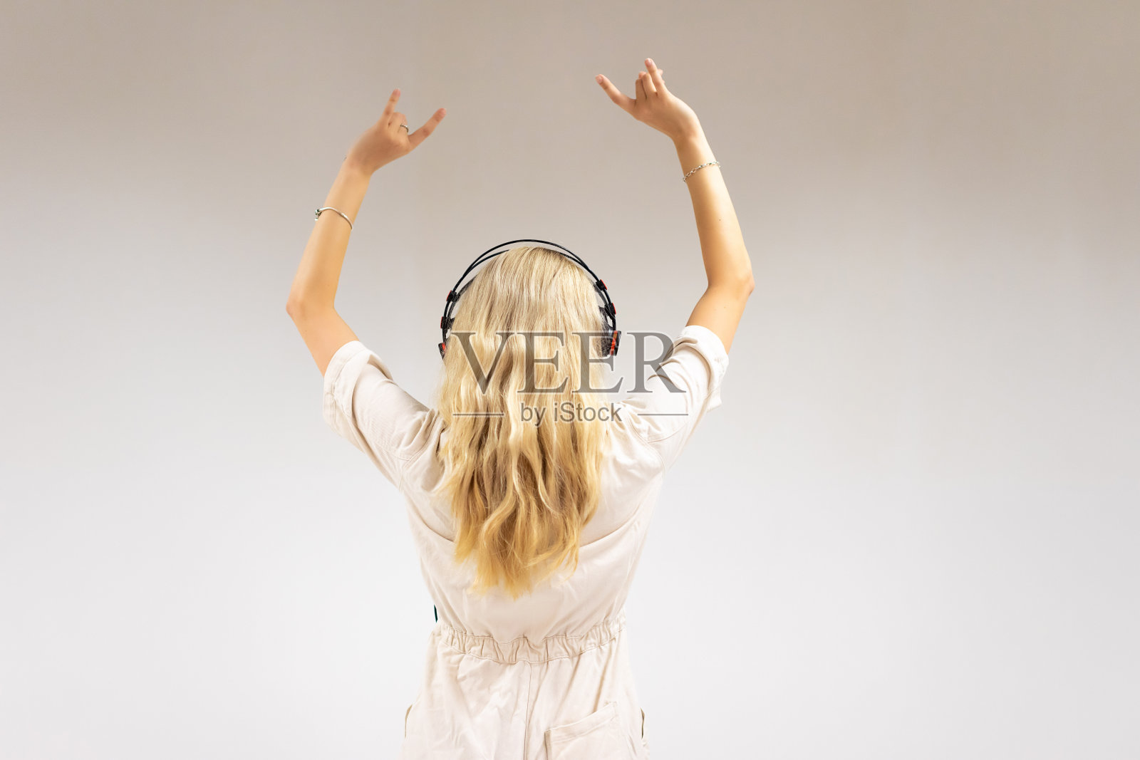 美丽的年轻金发女子在白色背景下听音乐照片摄影图片