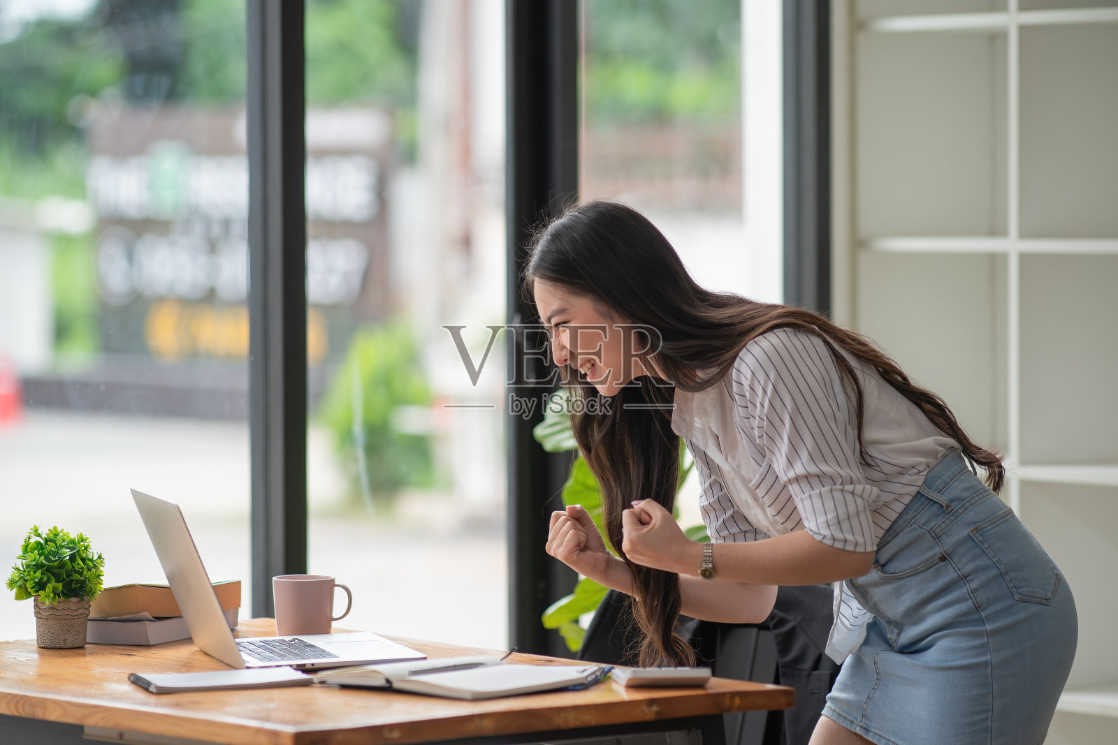 美丽的亚洲女商人在办公室用笔记本电脑庆祝和显示喜悦。照片摄影图片