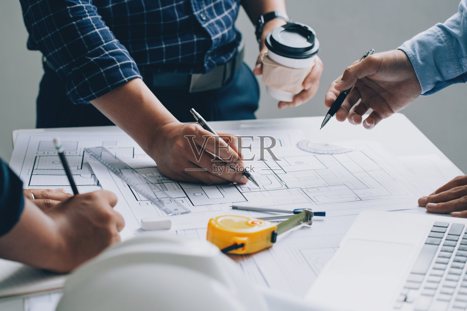 工程师或建筑师与合作伙伴召开项目会议，并在工作现场使用工程工具检查新项目的施工蓝图。照片摄影图片