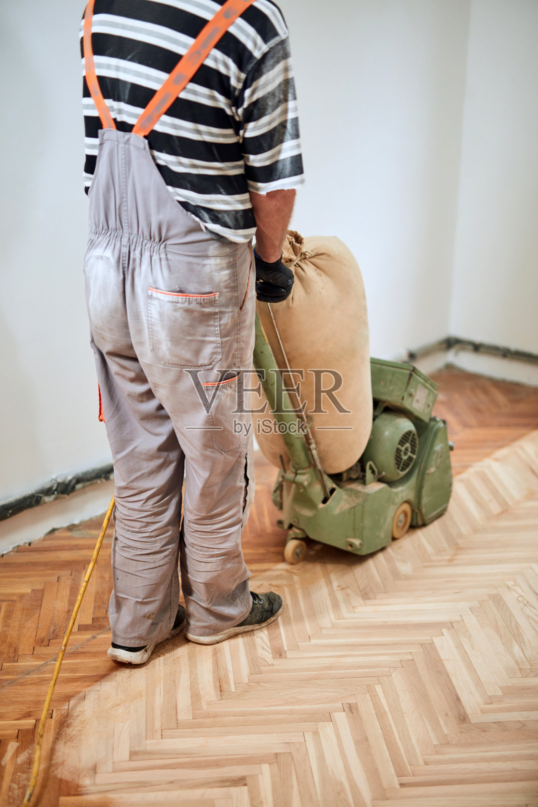 修理工用砂光机修复拼花地板。照片摄影图片