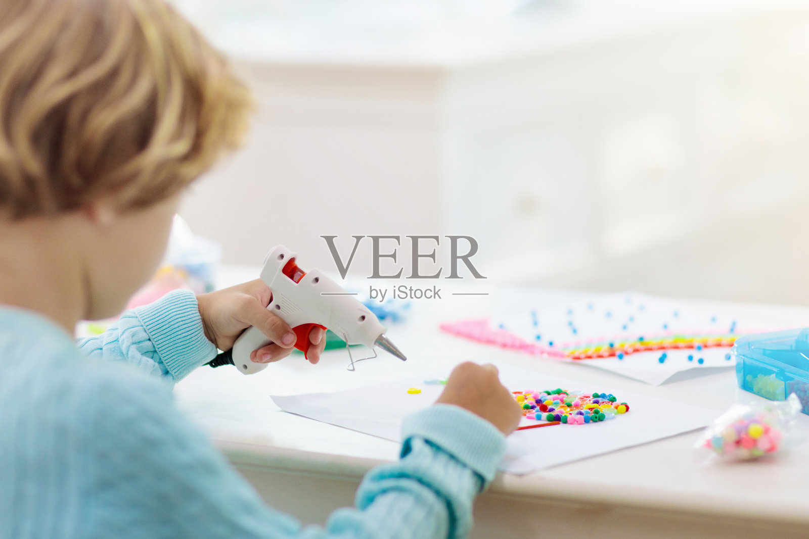 对孩子工艺品。小孩用热胶枪。照片摄影图片