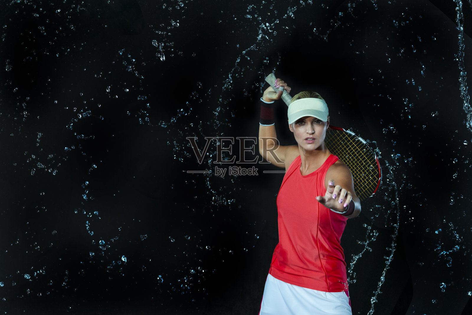 女网球选手用球拍摆姿势，在黑色背景下撞击水滴。水平的形象定位照片摄影图片