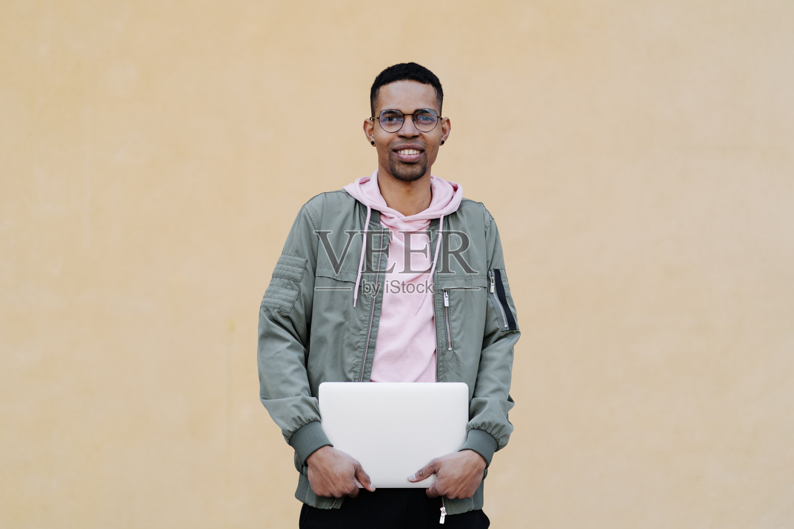 非洲男，戴眼镜，黄色背景上有笔记本电脑照片摄影图片