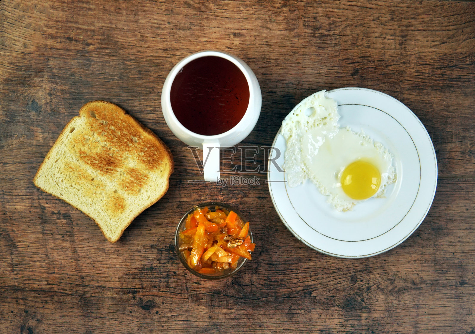 炒鸡蛋早餐，煎鸡蛋，一杯茶，果酱，木制背景烤面包。前视图。照片摄影图片