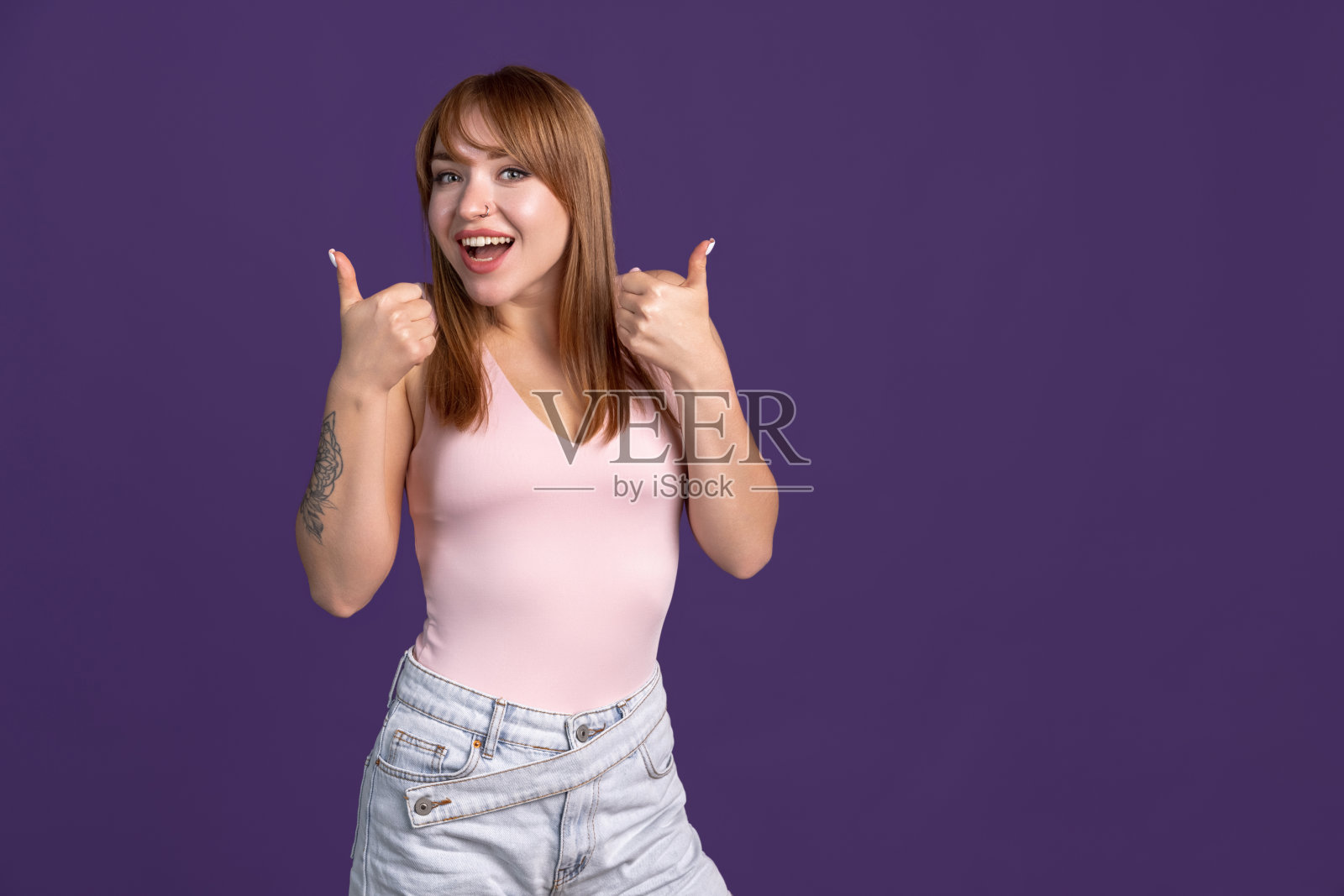 年轻快乐微笑的女孩的肖像孤立在紫色的工作室背景。人类情感概念，面部表情，青春，销售，广告。照片摄影图片