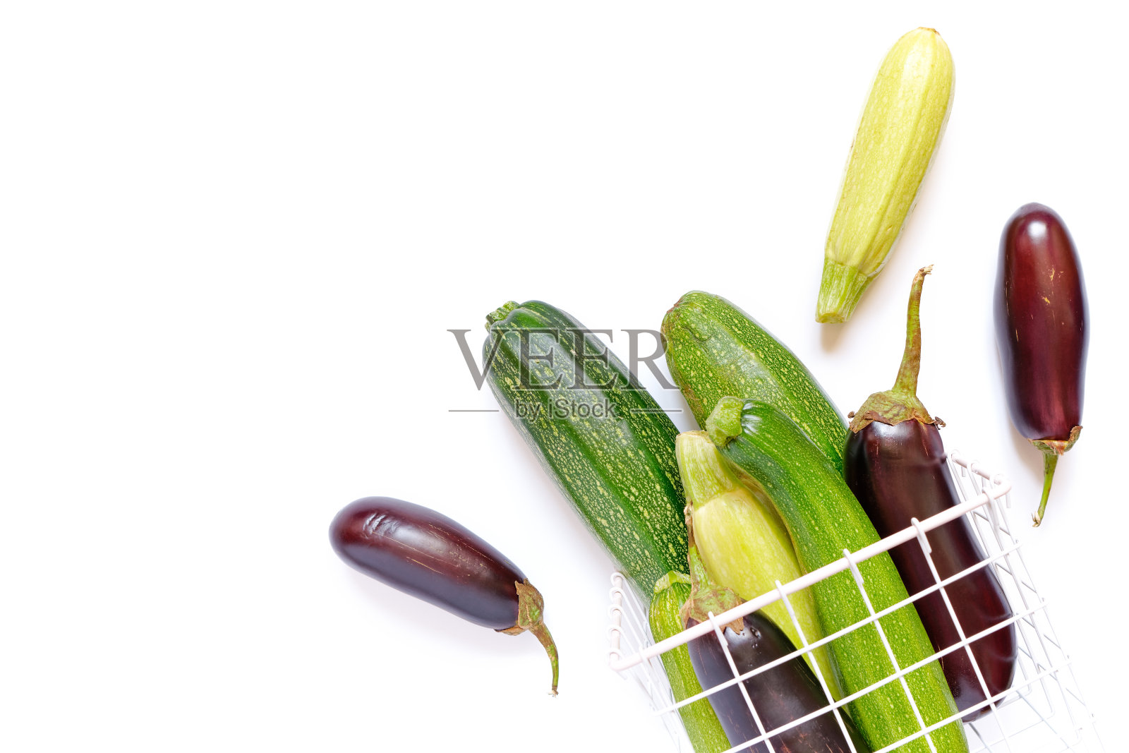 秋天作文用蔬菜。整个成熟的西葫芦和茄子放在白色背景的金属柳条篮子里。收割。食品配料。副本的空间。照片摄影图片