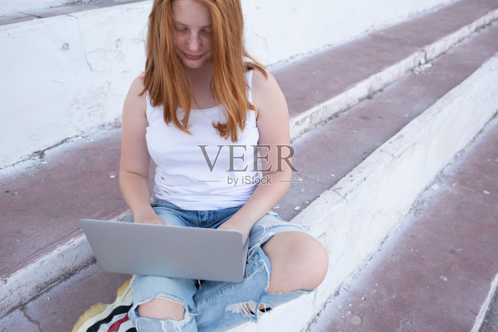 十几岁的女孩坐在台阶上用笔记本电脑工作照片摄影图片