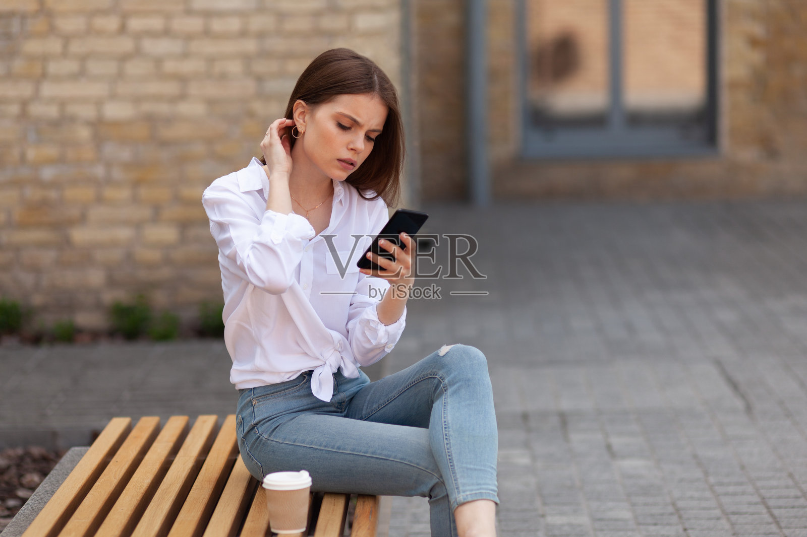 一个拿着智能手机的悲伤女人坐在外面。坏消息和问题，沮丧和精神痛苦照片摄影图片