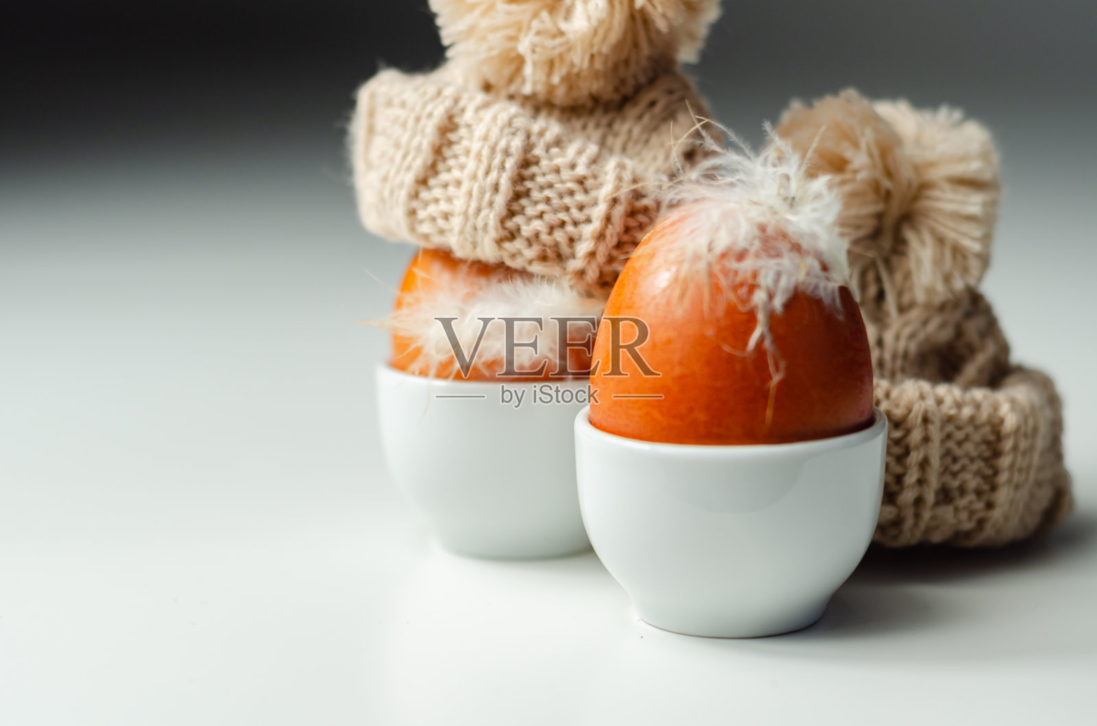 新鲜的自由放养的蛋，蛋杯上有天然羽毛，蛋上有羊毛帽，照片摄影图片