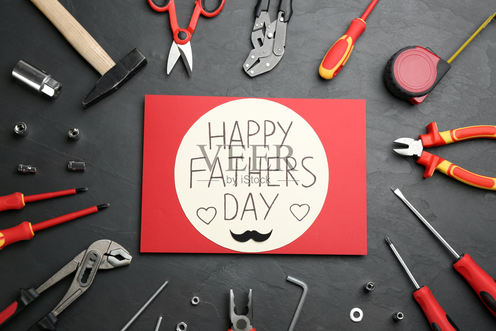 卡片上写着“父亲节快乐”，不同的工具放在石头背景上，平铺照片摄影图片