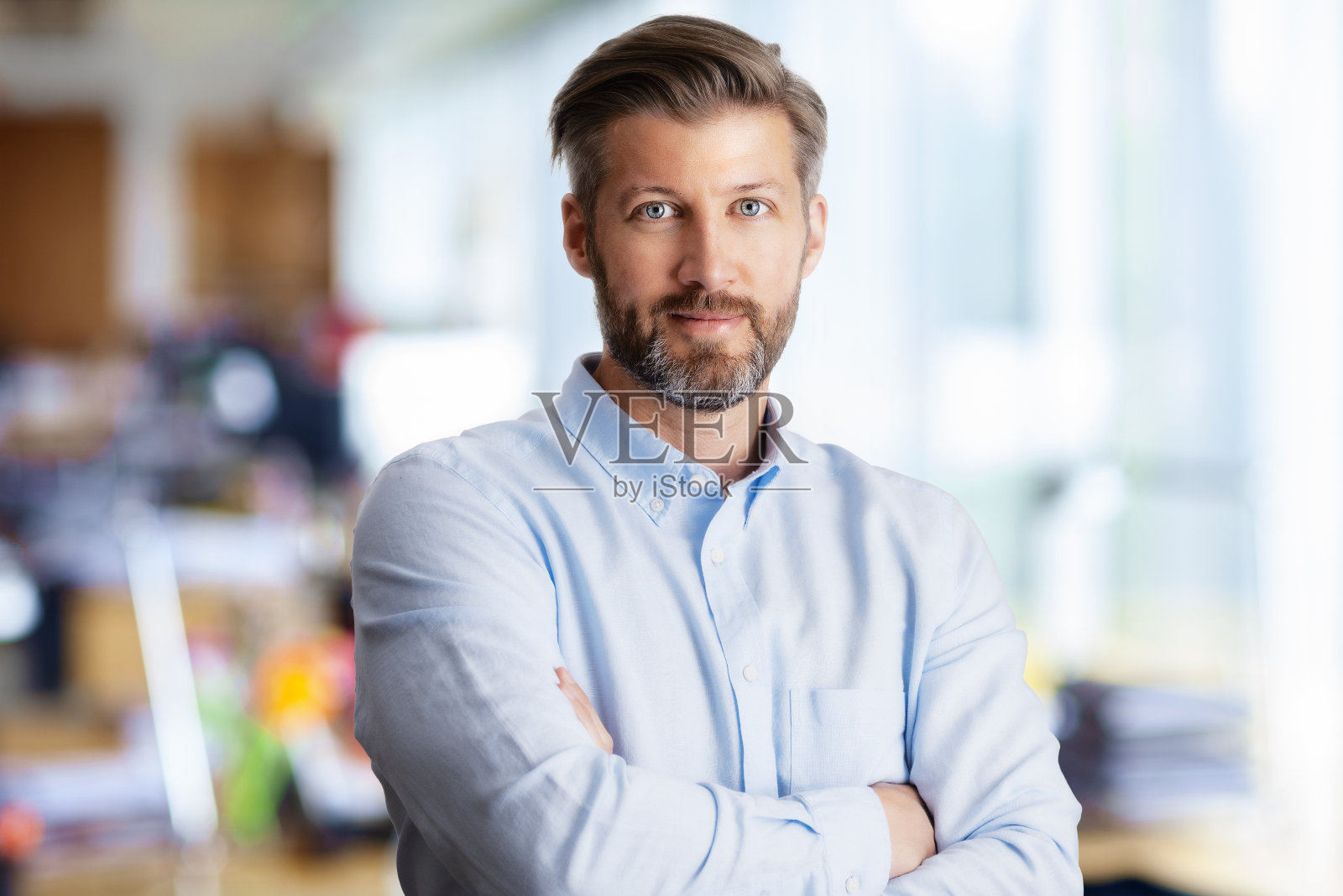 一个自信的商人，双臂交叉站在办公室里照片摄影图片