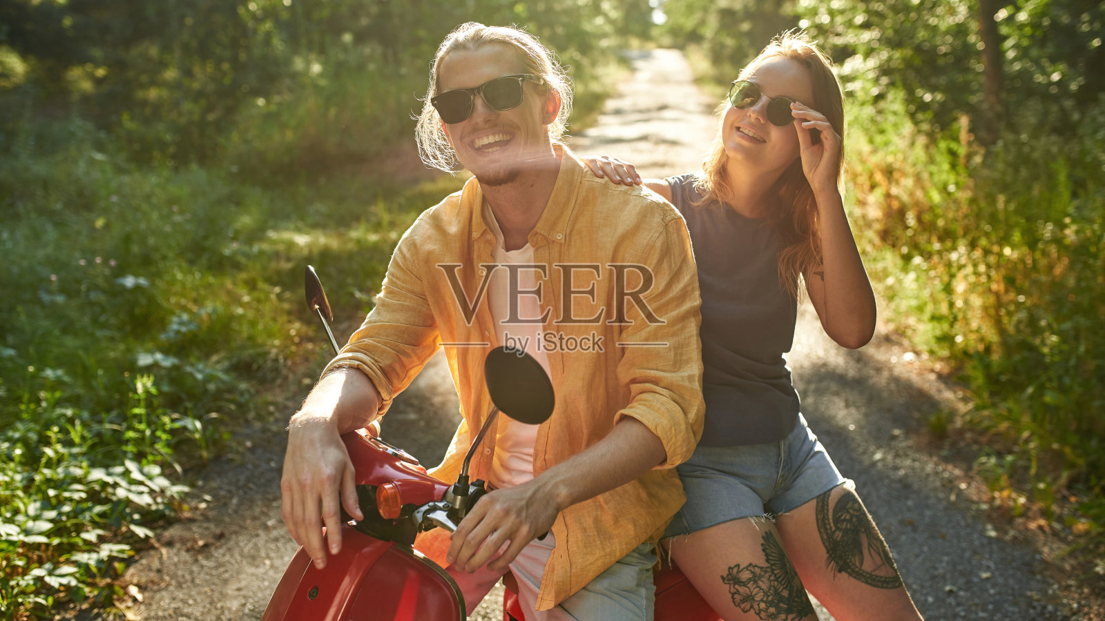 坐在滑板车上微笑的年轻白人朋友照片摄影图片