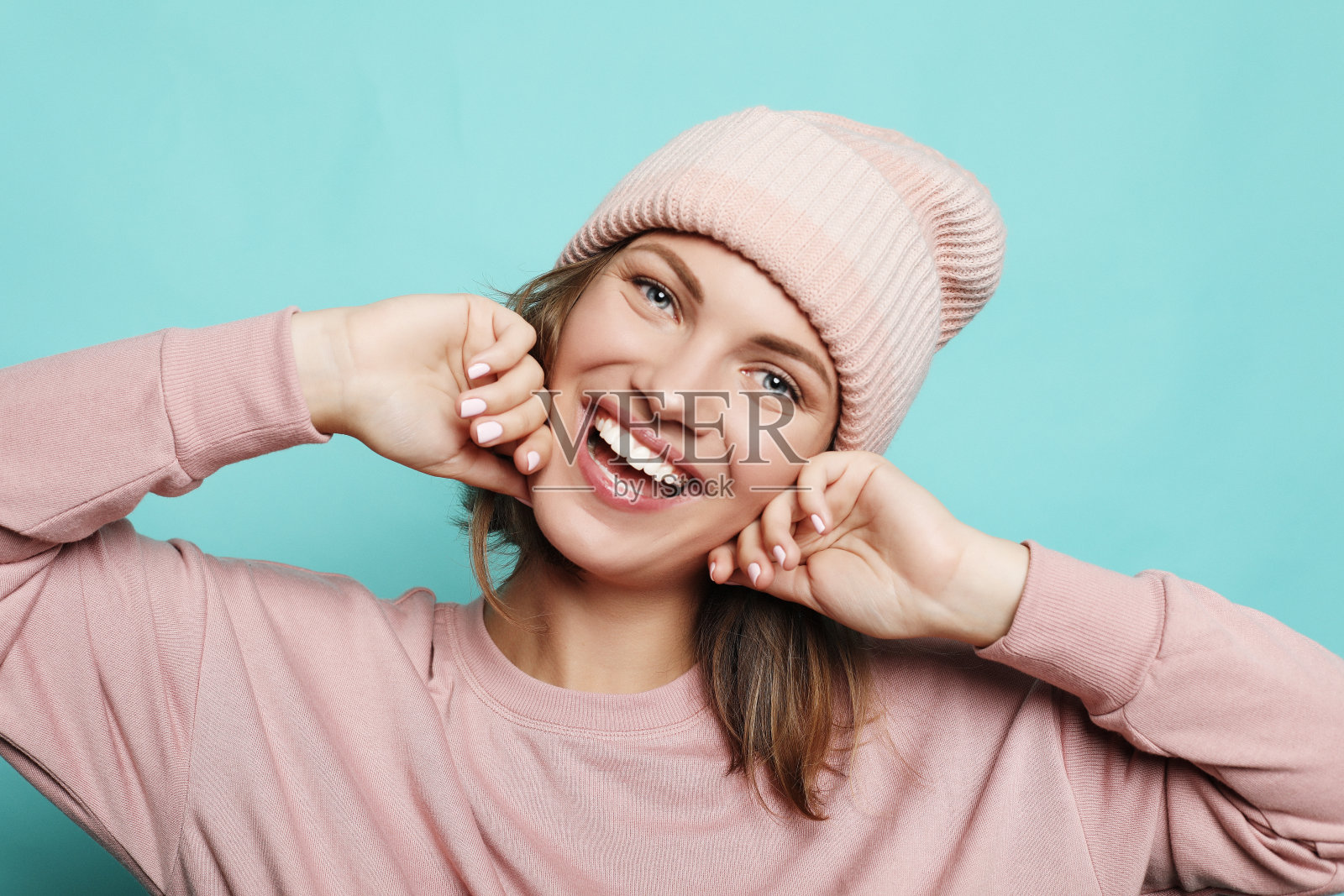 快乐的年轻女士穿着粉红色的帽子和毛衣的形象照片摄影图片