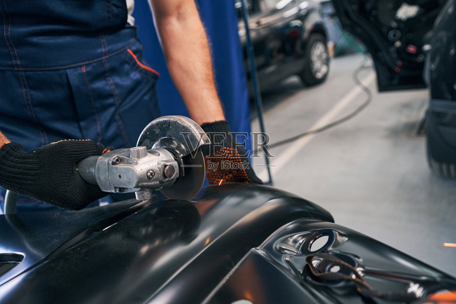 修理工用角磨机切割汽车零件的金属照片摄影图片