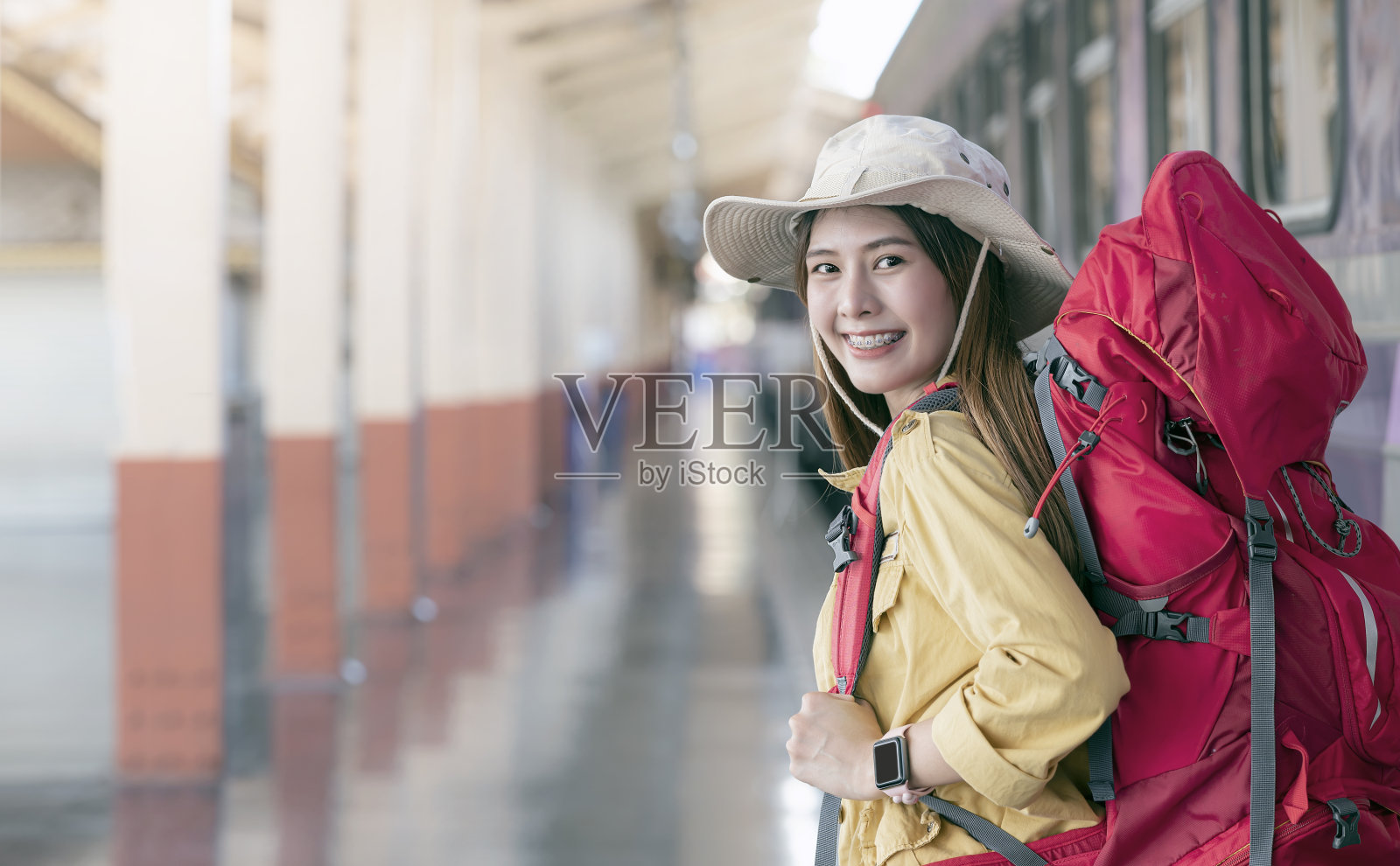 美丽的亚洲旅行者背着背包，微笑着看着相机，准备在火车站旅行。照片摄影图片