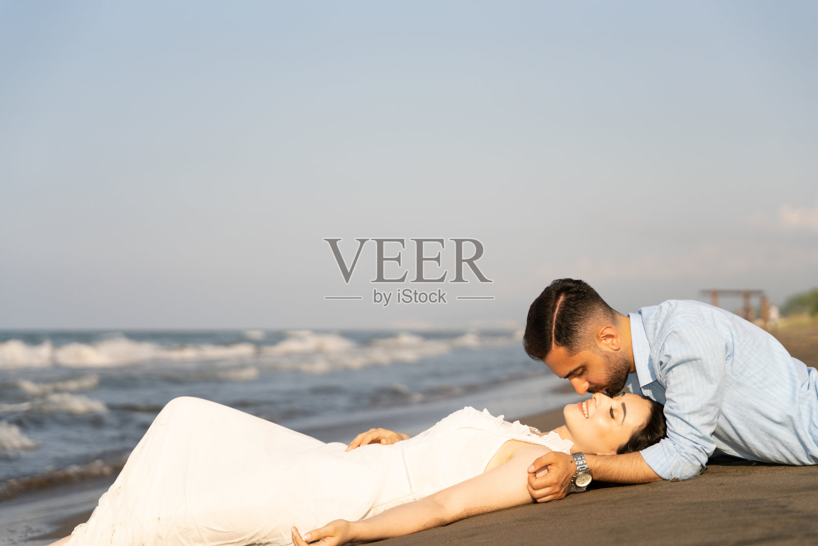 年轻情侣在沙滩上摆姿势。照片摄影图片