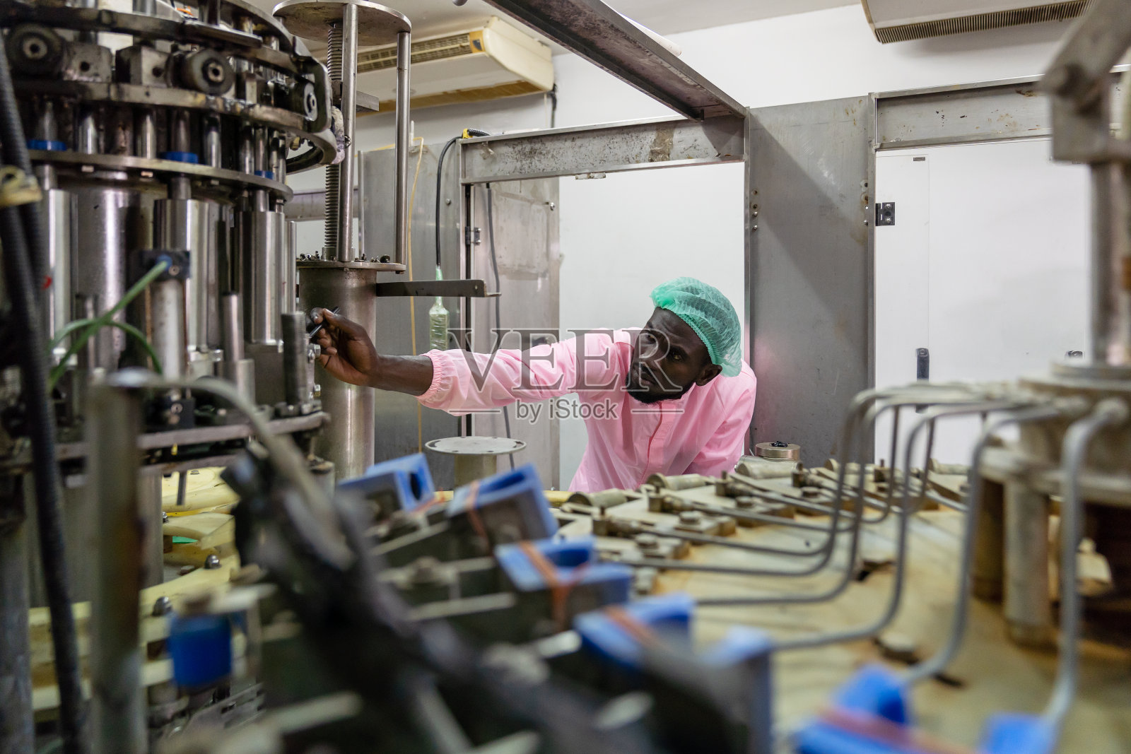 在饮料厂检查自动传送带的控制人员。非裔美国男性工程师，在工业工厂中使用或维护机器的工人照片摄影图片