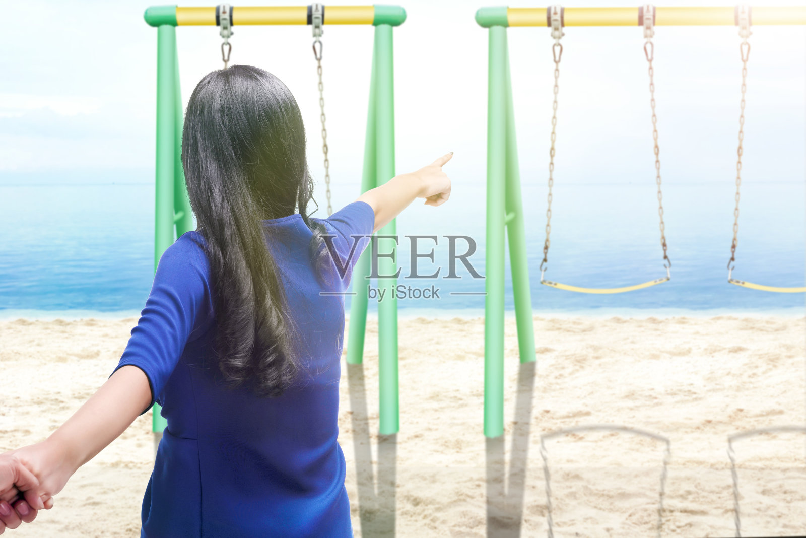 背面的亚洲女人牵着她男朋友的手在沙滩上和指向的观点照片摄影图片