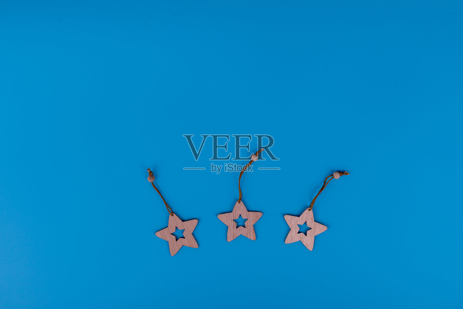 蓝色背景的新年和圣诞节木制玩具。激光切割木制星星小雕像。明信片组成与自由空间的文字。新年和圣诞节的概念。平铺有复制空间。照片摄影图片