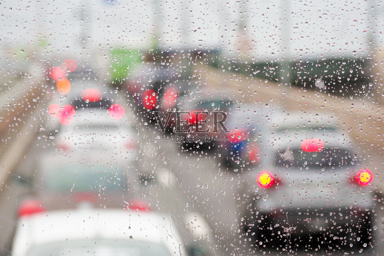 汽车在桥上行驶，城市在晚上下雨时交通堵塞。关注汽车挡风玻璃上的雨滴照片摄影图片