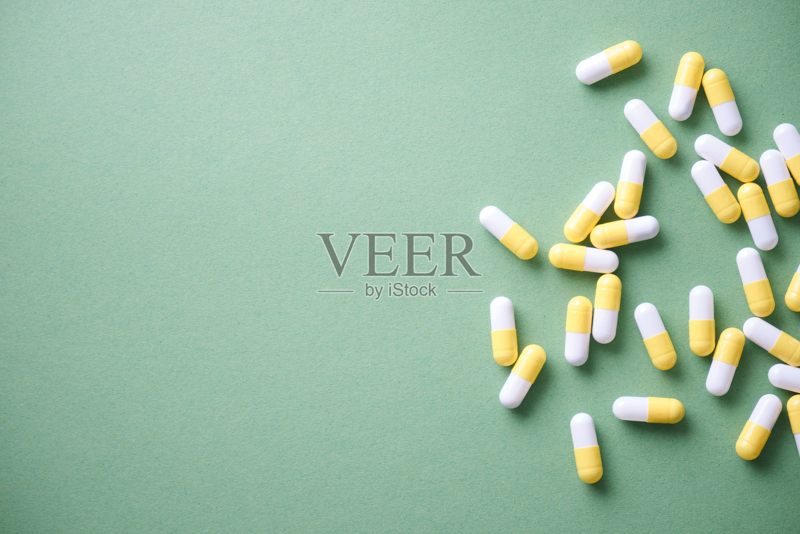 药片散落在桌子上。绿色背景上的平板。药用片剂、胶囊。照片摄影图片