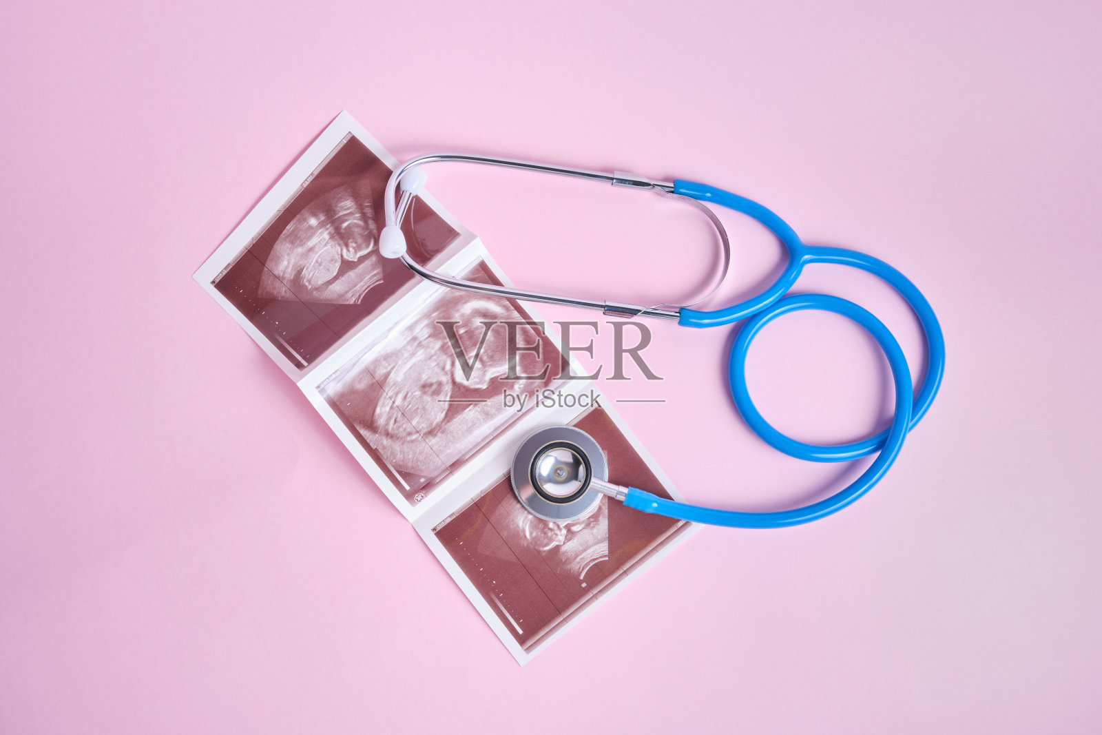 粉红色背景上的医学听诊器和胚胎图片照片摄影图片
