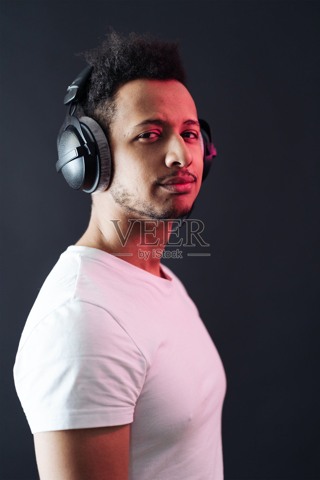 无忧无虑的深色皮肤的家伙肖像戴着耳机在黑色背景照片摄影图片