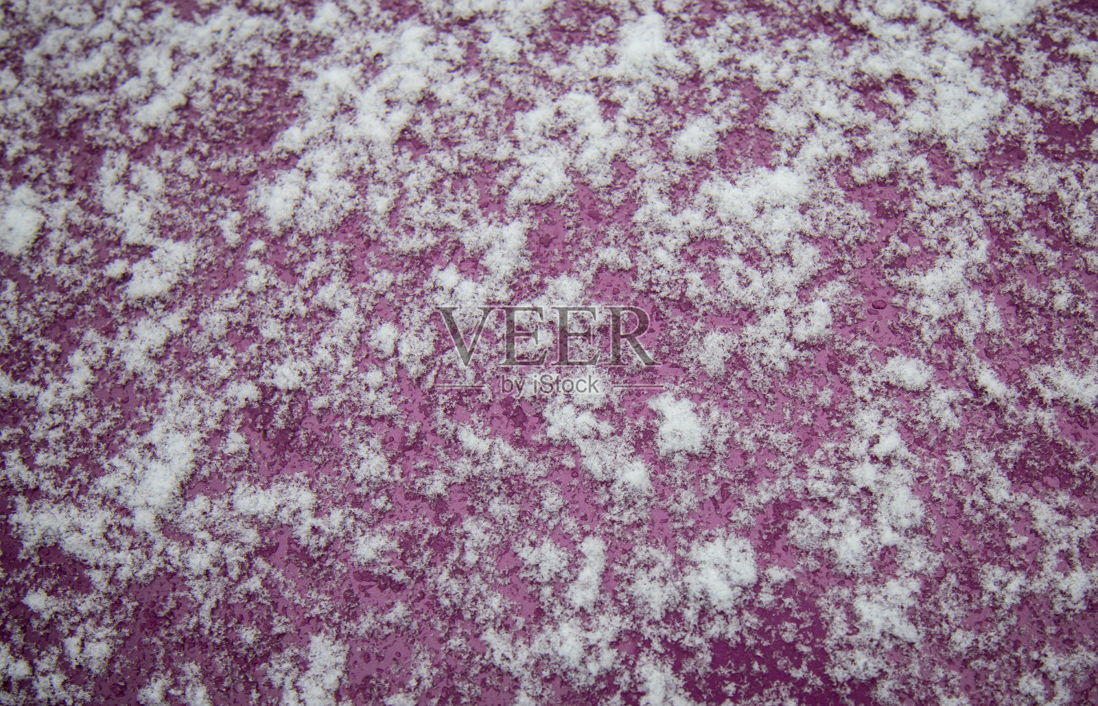 背景雪花在深红色的金属表面。汽车引擎盖上飘满了雪花照片摄影图片