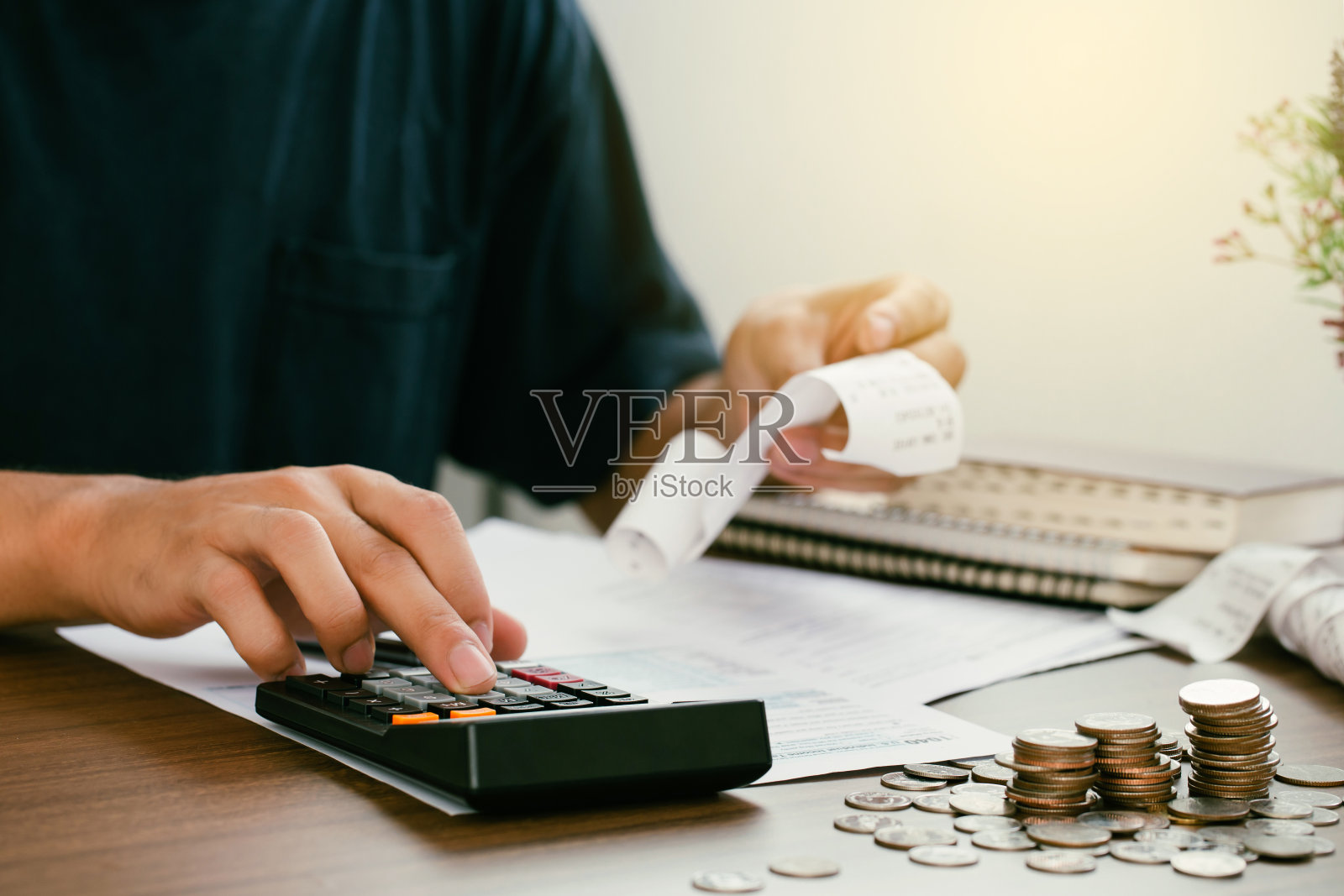 男人在家里计算家庭账单。在现代化的办公室里，一名男子正在用计算器核对余额和成本。商务人员在做纳税文书工作。税收的概念照片摄影图片