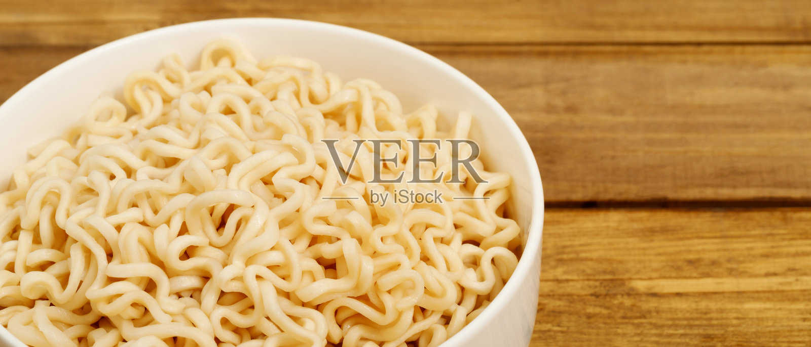 方便面被放在餐桌上的一个白色杯子里。照片摄影图片