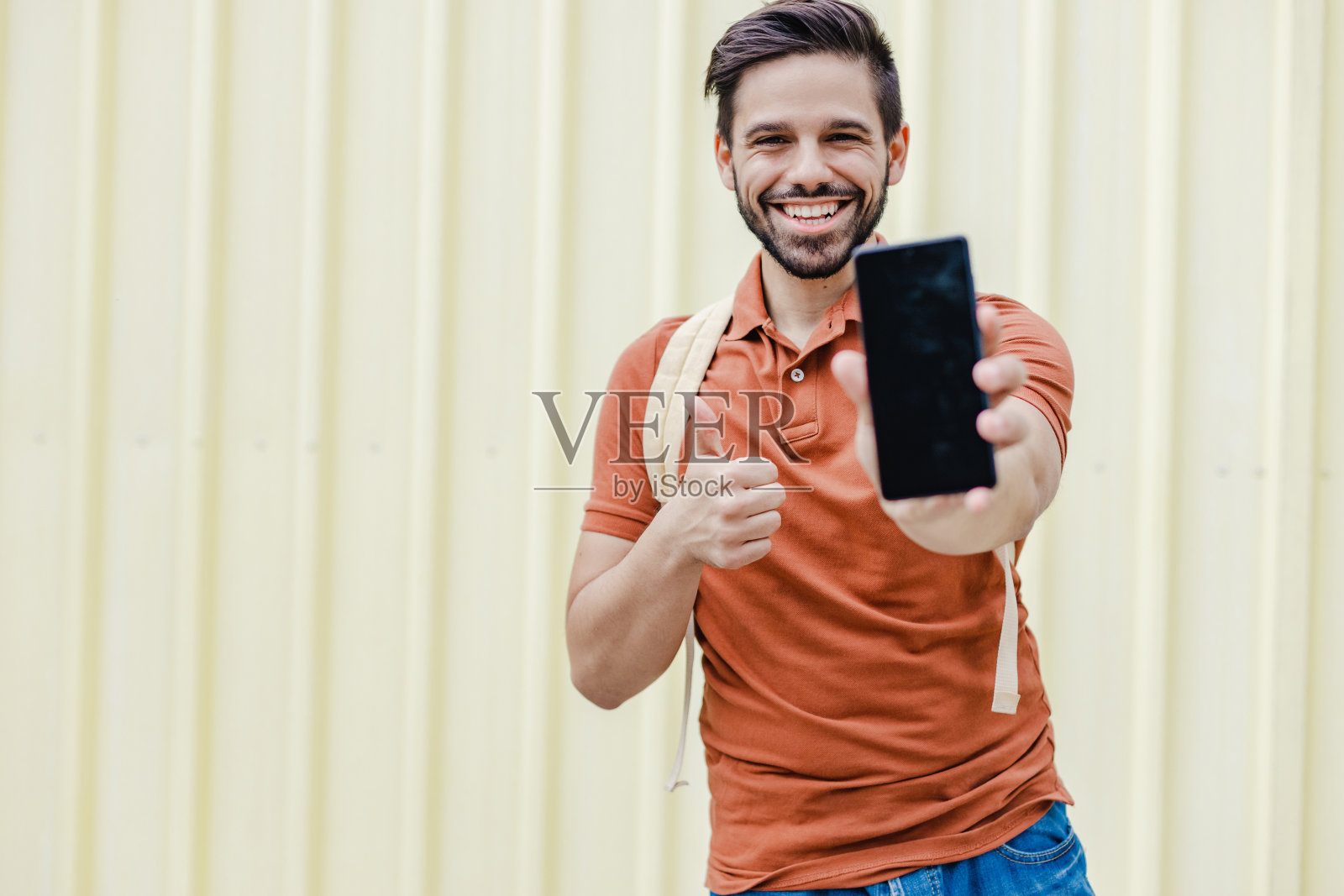 年轻男子手持手机微笑的肖像照片摄影图片