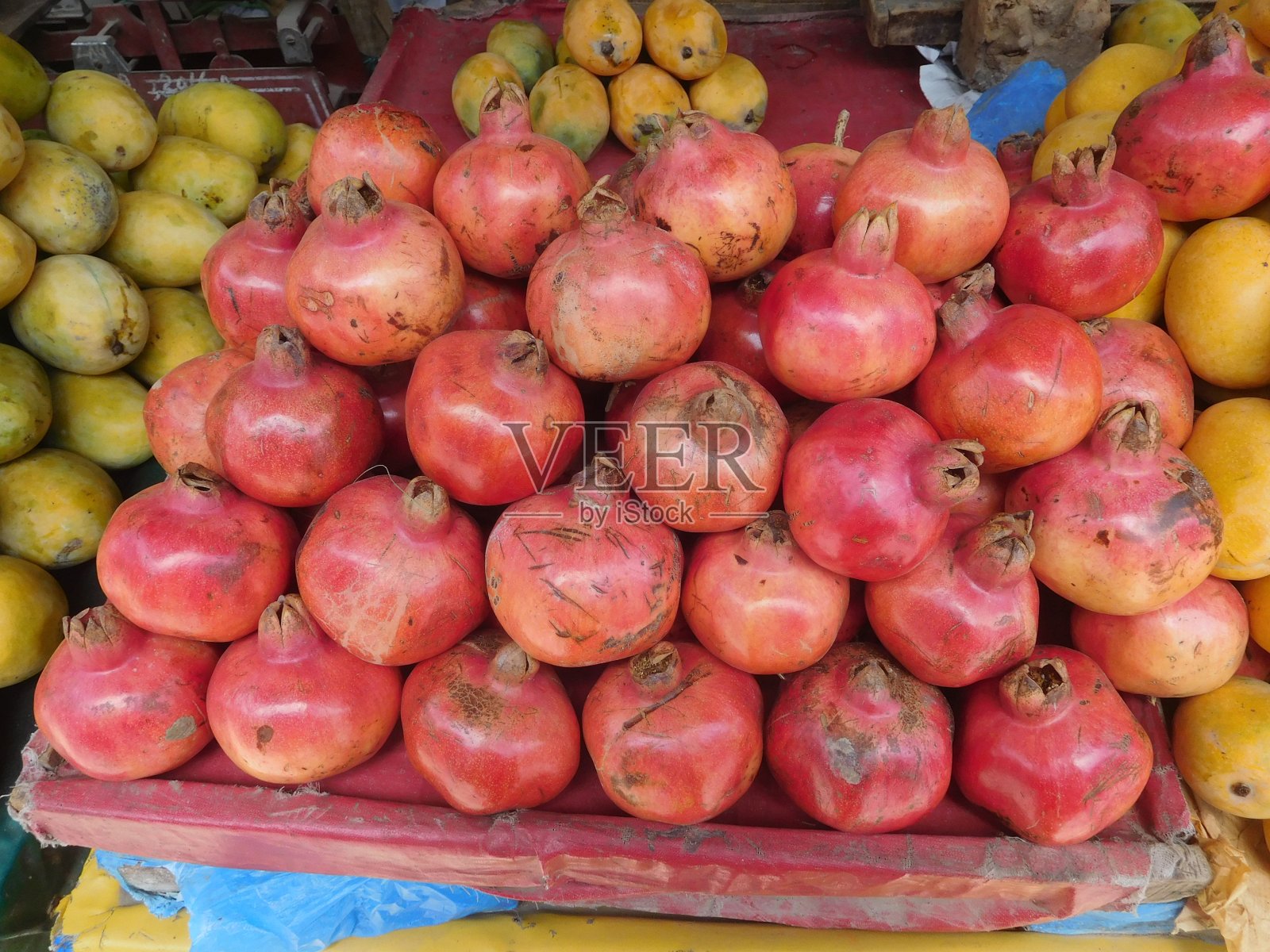 石榴果实熟透，红色，堆放在市场零售场所。水果和蔬菜摊位或商店的一堆石榴的特写镜头照片摄影图片