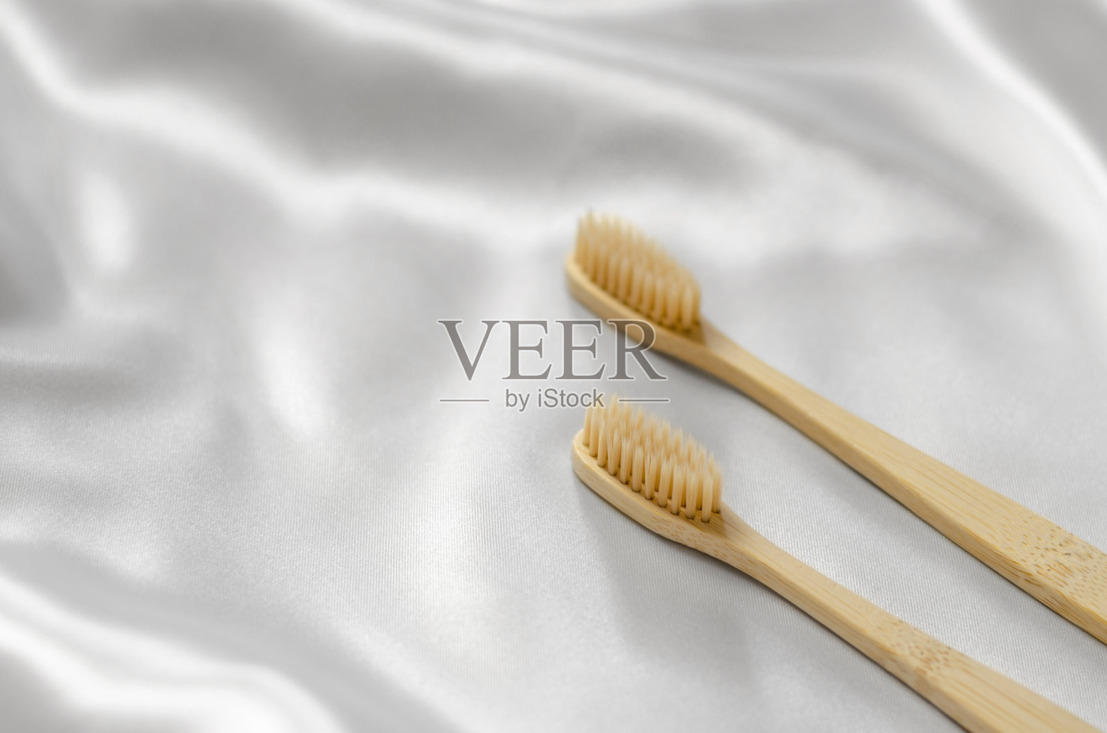 木制牙刷在丝绸织物上，有选择性的焦点。口腔护理。环保个人卫生产品。照片摄影图片