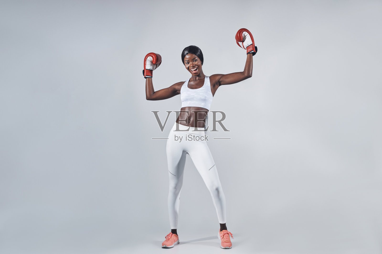 漂亮的年轻非洲妇女戴着拳击手套，举起双臂照片摄影图片