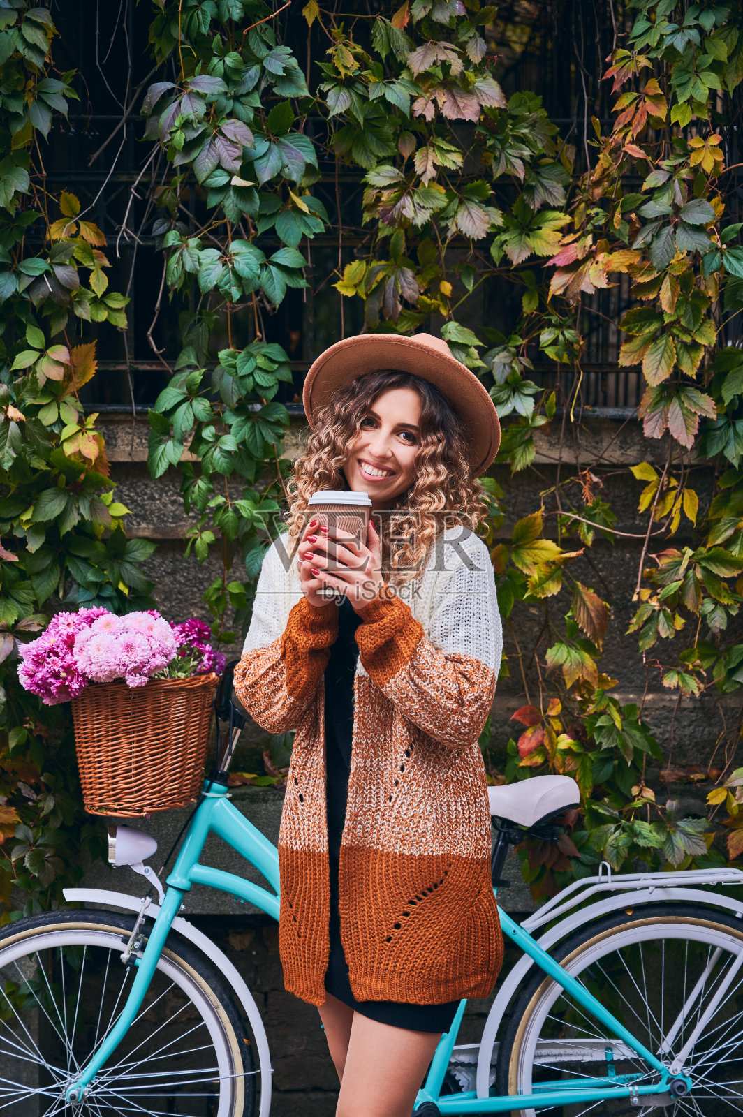 快活的女人端着咖啡站在自行车旁。照片摄影图片
