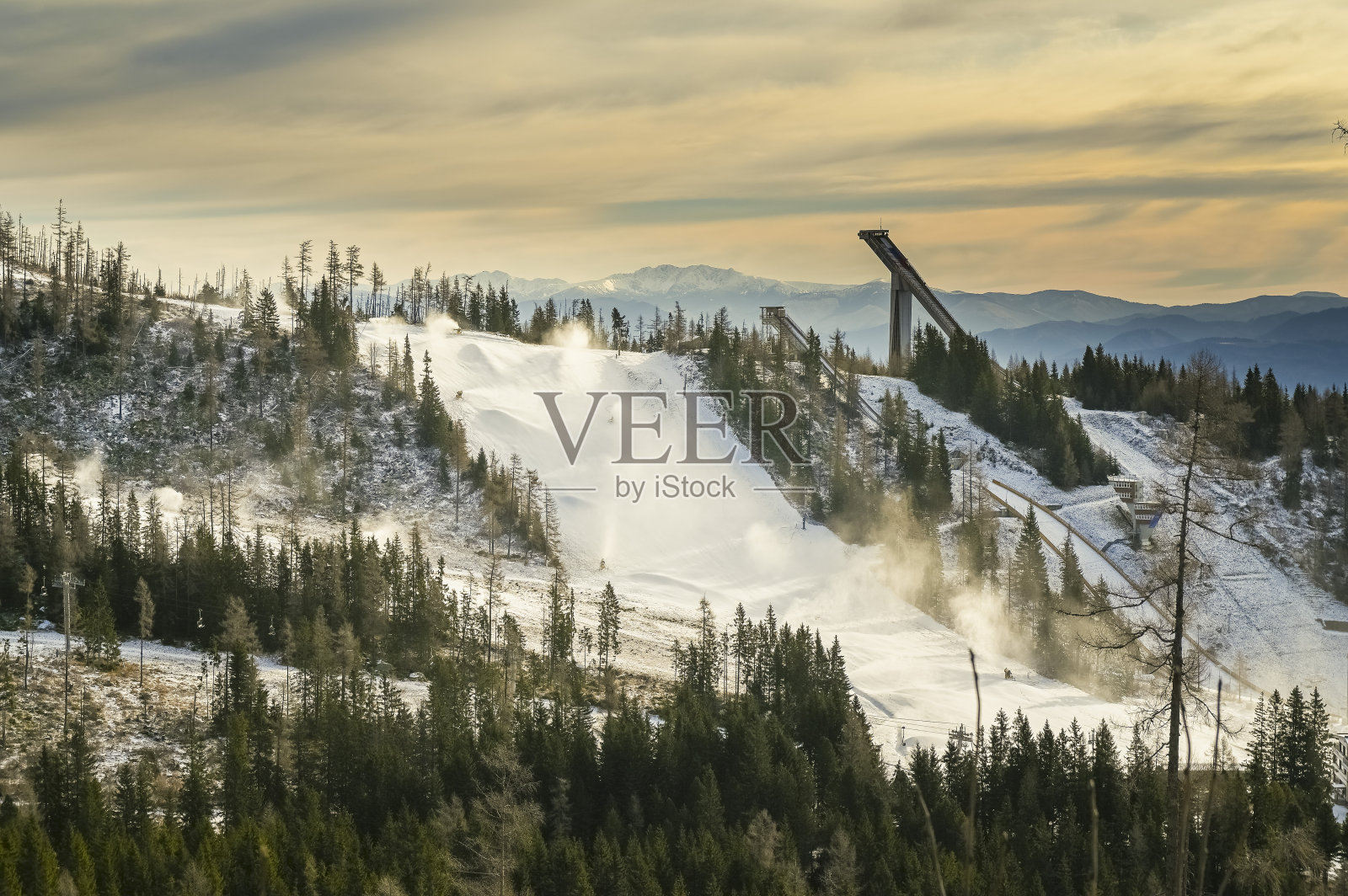 冬天山上的雪炮。雪枪喷洒人造冰晶。机器使雪。照片摄影图片