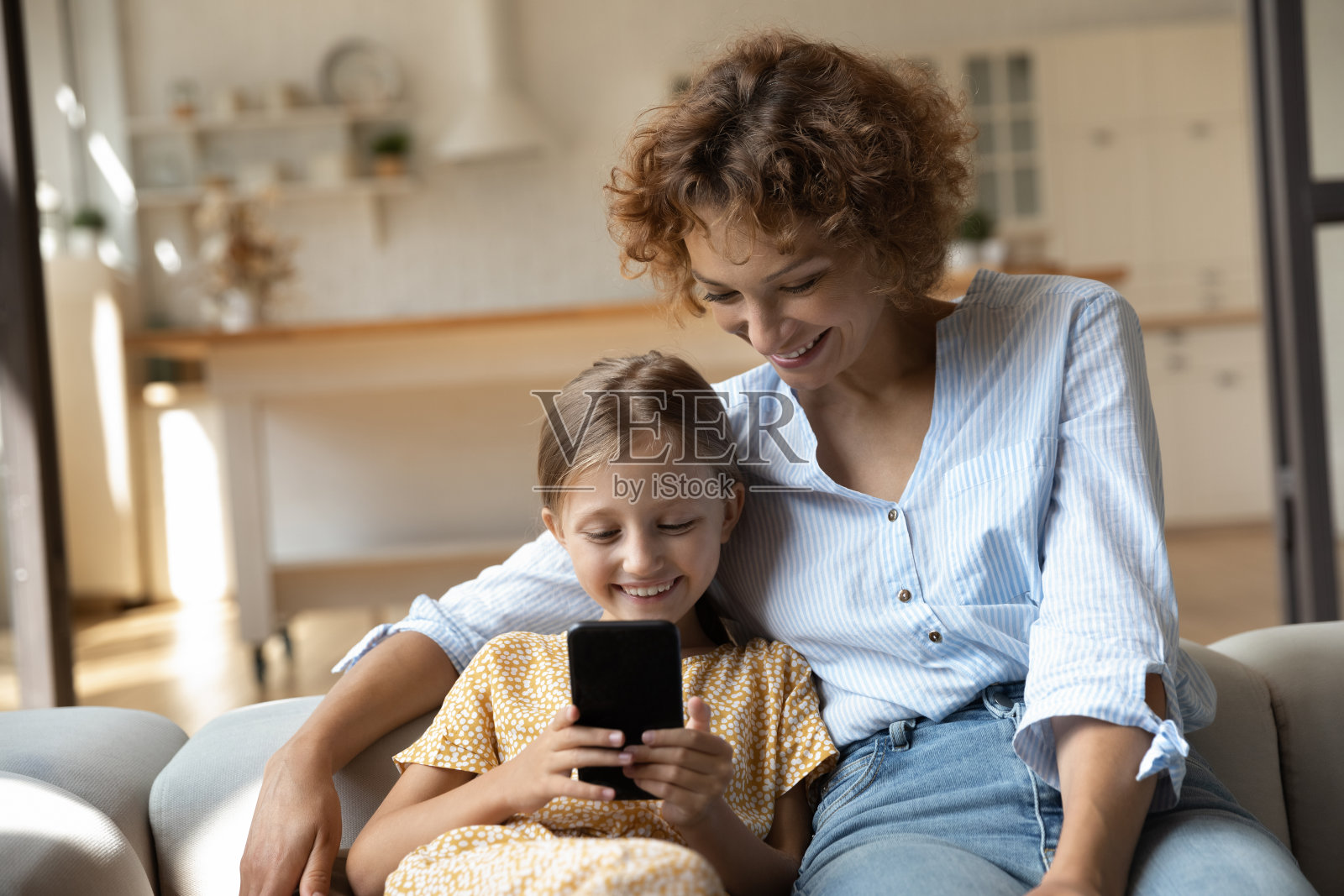 靠近兴奋的母亲和正在使用智能手机的小女儿照片摄影图片