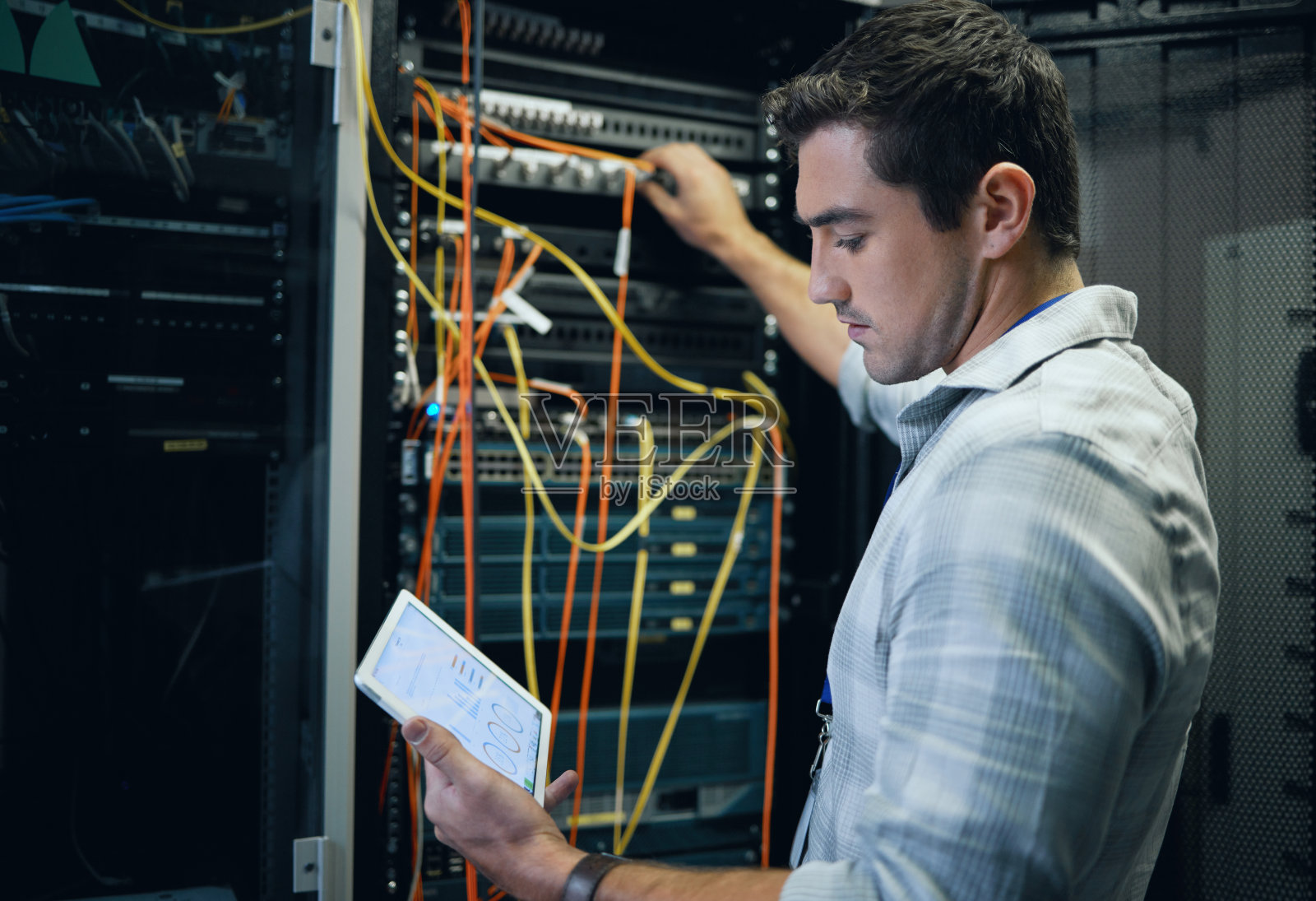 一个英俊的年轻男性程序员在服务器室开发平板电脑的裁剪照片照片摄影图片