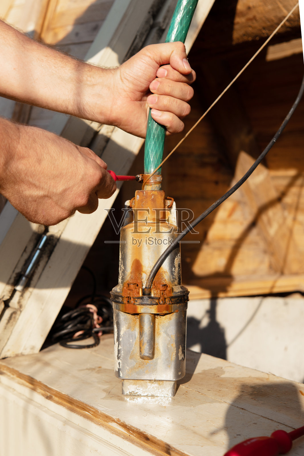 公手使用软管夹将井泵与软管连接起来照片摄影图片